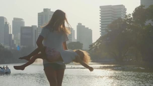 Familia divirtiéndose en el parque con lago y rascacielos en el fondo — Vídeo de stock