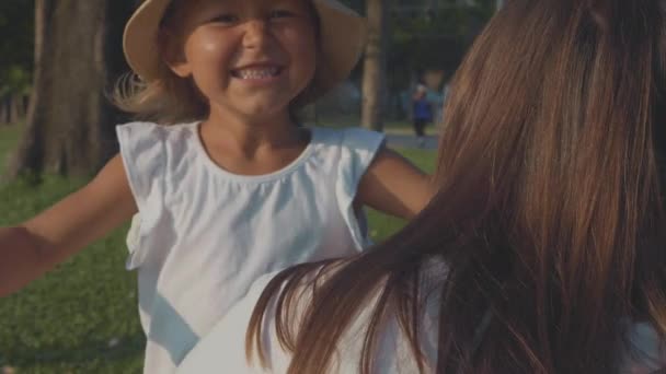 Little child running into her mothers hugs at the park in slow motion. — Stock Video