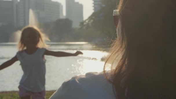 Criança correndo para suas mães abraços no parque em câmera lenta . — Vídeo de Stock