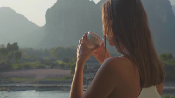 Mujer joven bebiendo café caliente en el balcón con hermoso paisaje de montaña — Vídeo de stock