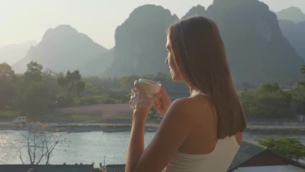 Mujer joven bebiendo café caliente en el balcón con hermoso paisaje de montaña — Vídeo de stock