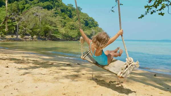 Feliz niña riendo balanceándose en la playa tropical de arena — Foto de Stock