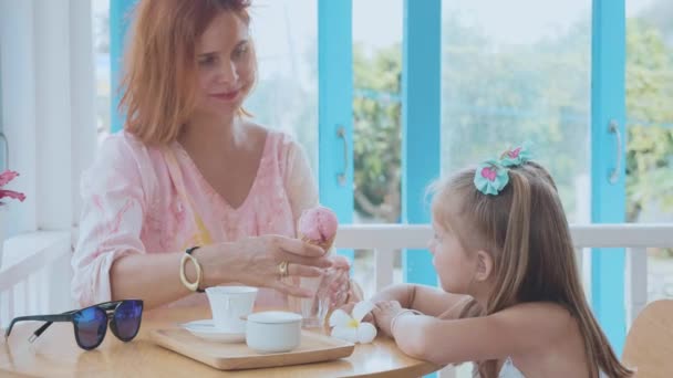 Young mother and her little daughter spending time in a cafe with ice cream — Stock Video