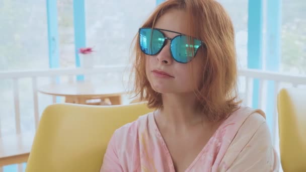 Портрет чарівної молодої жінки в сонцезахисних окулярах в приміщенні в повільному русі — стокове відео