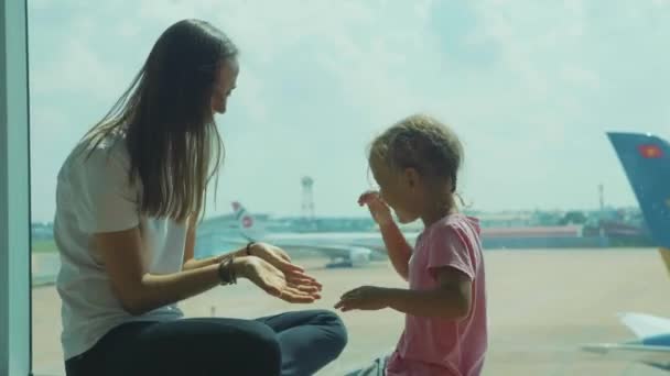 Yound mor och lilla söta dotter ha kul på flygplats. — Stockvideo