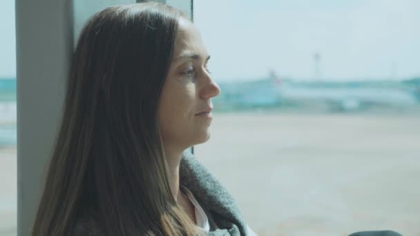 Joven mujer triste está llorando en el aeropuerto con el avión en el fondo — Vídeos de Stock