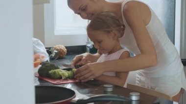 Genç anne küçük kızı iç mutfak pişirme öğretim.