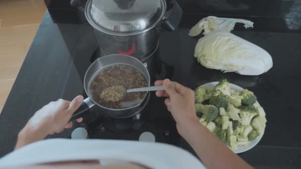 Punto de vista de la mano con cuchara revolviendo lentejas hirviendo para sopa de verduras, primer plano . — Vídeo de stock