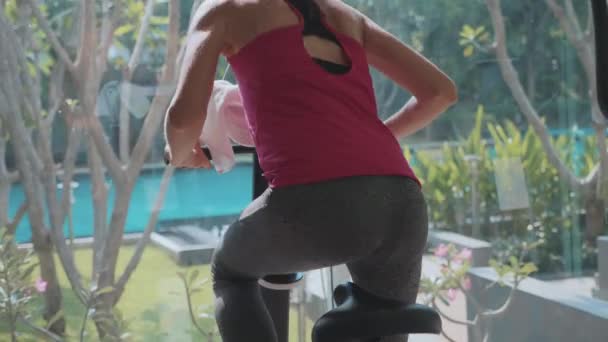 Primer plano piernas femeninas y culo a caballo en bicicleta estacionaria en el gimnasio en cámara lenta — Vídeos de Stock