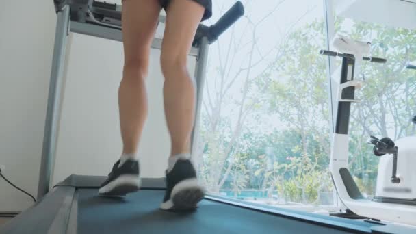 Спортивна молода жінка біжить на біговій доріжці, крупним планом вид ззаду — стокове відео