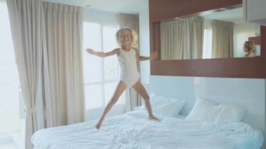 Küçük çocuk kız yatak yatak odası, ağır çekimde sabah atlama