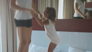 Küçük kızı yatakta sabah birlikte atlama ile genç anne