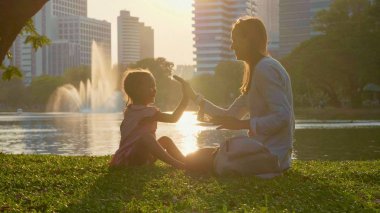 Aile göl ve arka planda gökdelenler ile parkta eğleniyor