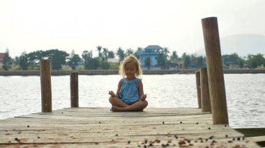 Lotus poz ve meditasyon ahşap iskele kız çocuk oturur