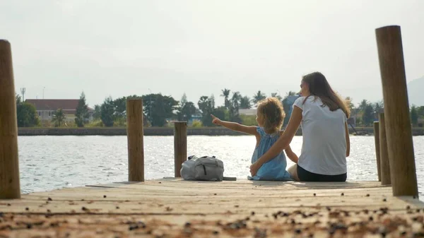 桟橋と自然を楽しんで座っている小さな娘を持つ母 — ストック写真