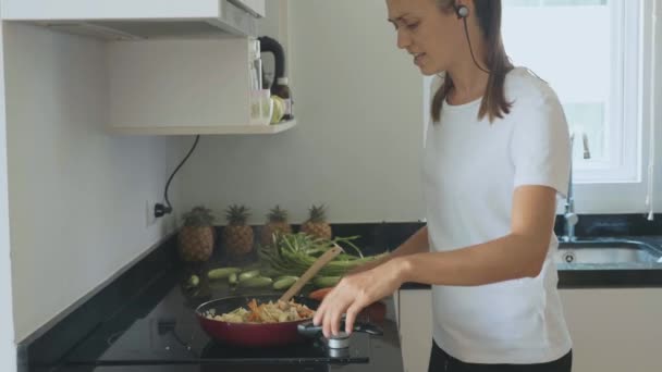 Ung kvinna dansar och sjunger medan matlagning på inhemska kök — Stockvideo