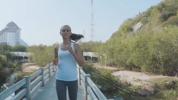 Young woman jogging on mangroves forest path. Steadicam shot in slow motion — Stock Video