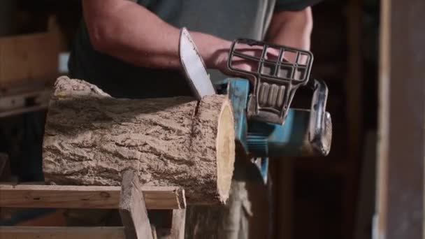 De mens zaagt een hout met een elektrische kettingzaag bij timmerwerk — Stockvideo