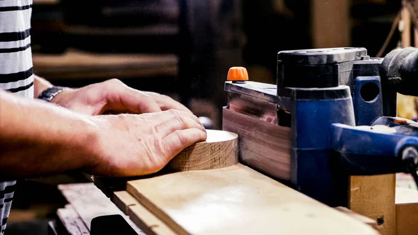Craftsman working with grinding machine at wood workshop, hands closeup. — Stock Photo, Image