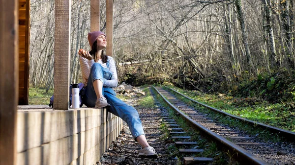 Mulher mochileiro jovem está sentado na estação de trem e comer maçã — Fotografia de Stock