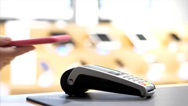 Lähikuva naisten käsi maksaa matkapuhelimella NFC siru pankkipäätteellä — kuvapankkivideo