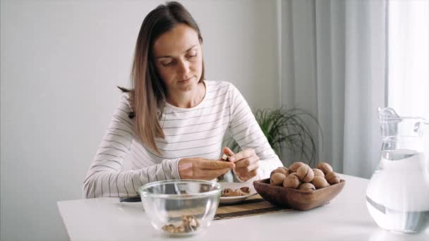 Mujer joven está agrietando unas nueces en la habitación doméstica — Vídeos de Stock