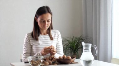 Genç bir kadın ev odasında ceviz kırıyor.