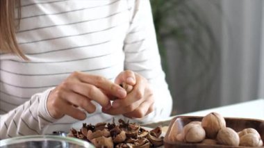 Genç bir kadın ev odasında ceviz kırıyor.