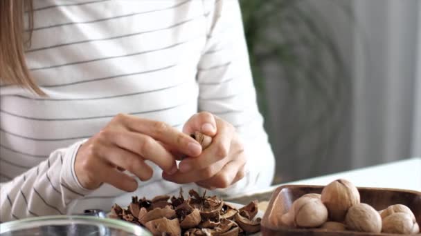 Mujer joven está agrietando unas nueces en la habitación doméstica — Vídeos de Stock