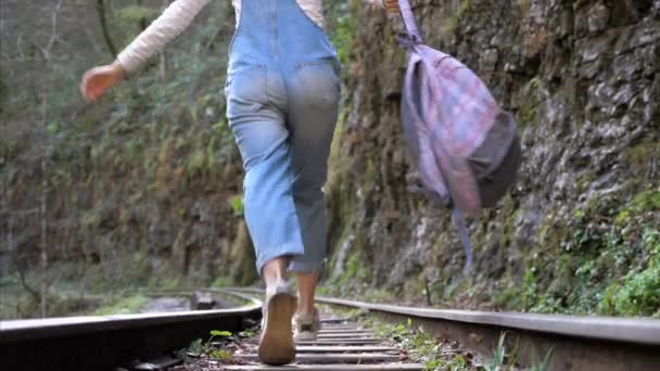 Молодая женщина турист радуется и работает на железнодорожных рельсах в одиночку, вид сзади — стоковое видео