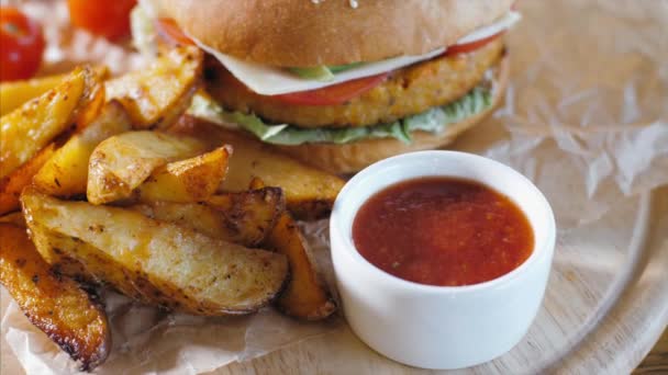 Patatas rústicas crujientes con hamburguesa sobre tabla de madera. Concepto de comida rápida . — Vídeo de stock