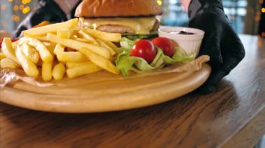 Garson masaya patates kızartması ve ahşap tahtaya hamburger koydu..