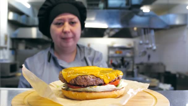 A női séf egy finom sajtburgert készít az éttermi konyhában. — Stock videók