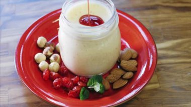 Chef is pouring a jam in jar with sweet dessert.
