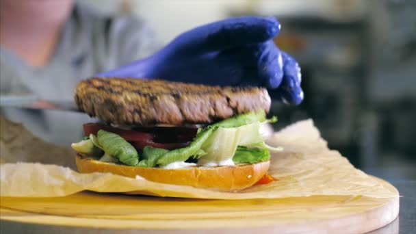 Close-up shot of chefs hands preparing a delicious burger with cheese. — Stock Video