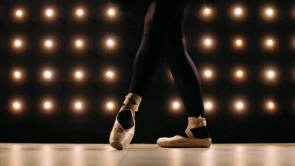 Voeten van ballerina in puntschoenen danst ballet in de donkere studio. — Stockvideo