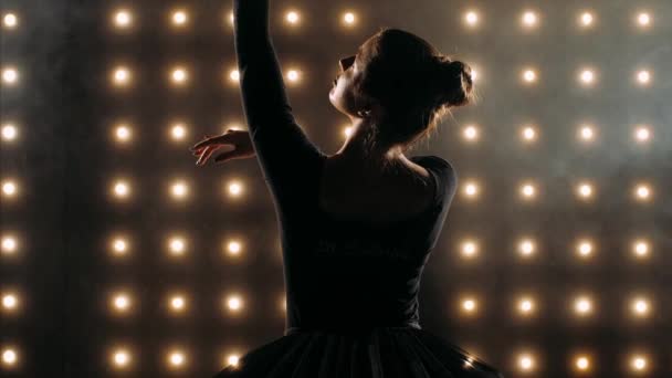A fekete ruhás balerina sziluettje balettozik a sötét stúdióban.. — Stock videók