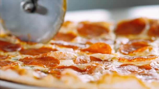 Womans hand slicing the salami pizza into slices using a roller pizza cutter — Stock Video