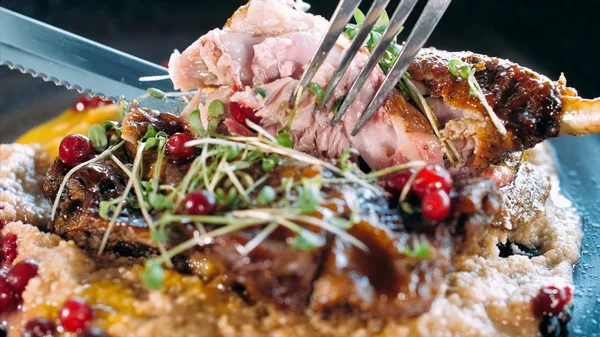 Крупный план нарезки аппетитной жареной утки вилкой и ножом — стоковое фото