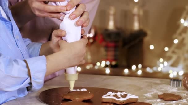 Madre con hijo se decora una Navidad galletas de jengibre con bolsa de pastelería — Vídeo de stock