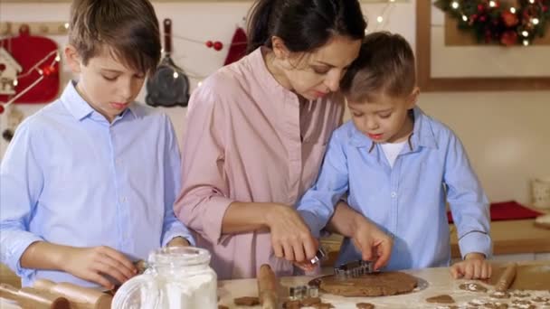 母を持つ子供たちはクリスマスにクッキーを焼くための生地を形成しています. — ストック動画