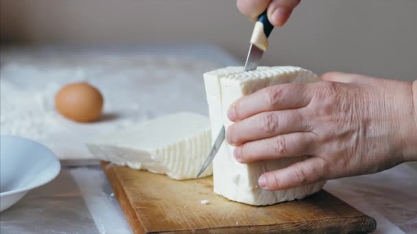 Close-up female hands is cutting a cheese for bakery preparation — 비디오