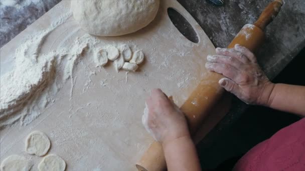 Närbild händer senior hona rullar en deg för dumplings hemma kök — Stockvideo