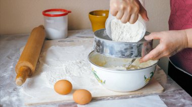 Olgun kadın hamur hazırlamak için çelik kaseye un ekliyor.