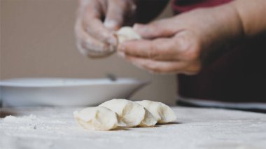 Olgun kadın elleri ev mutfağında peynirli hamur tatlısı yapıyor.