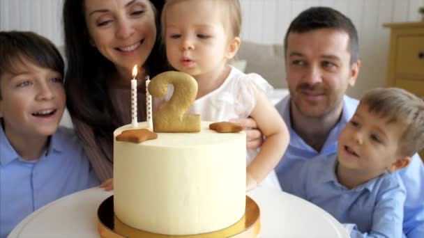 Linda niña está soplando las velas en el pastel de cumpleaños — Vídeos de Stock
