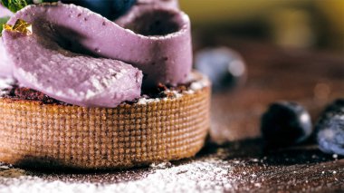 Cake with purple cream on the table near the blueberries, close-up.