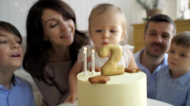 Schattig klein meisje blaast de kaarsen op verjaardagstaart — Stockvideo