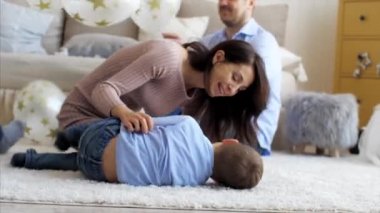 Happy mom is tickling her little laughing son on the floor, close-up