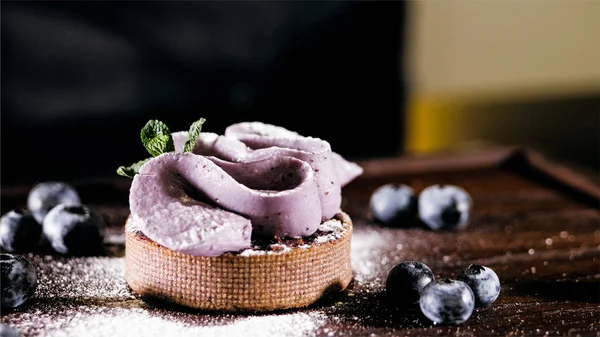 Торт с фиолетовым кремом на столе рядом с черникой, крупным планом . — стоковое фото